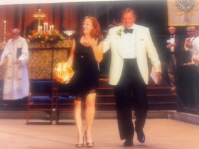 Nick and Marla walking down the aisle in a church, with Marla holding a bouquet.