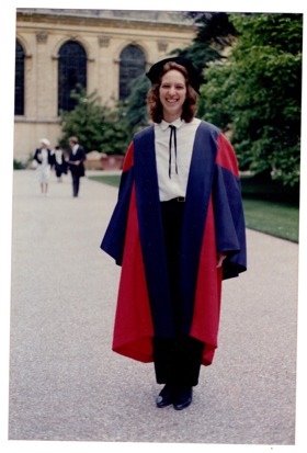 The picture shows Joy in a graduation gown with Trinity College in the background