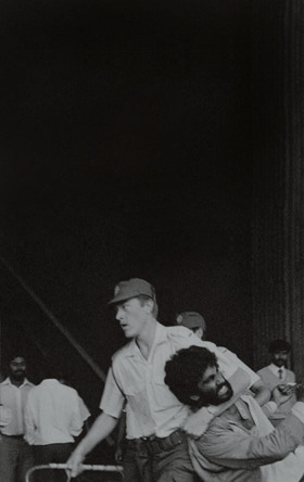 A black-and-white picture showing a policeman dragging Kumi by his neck