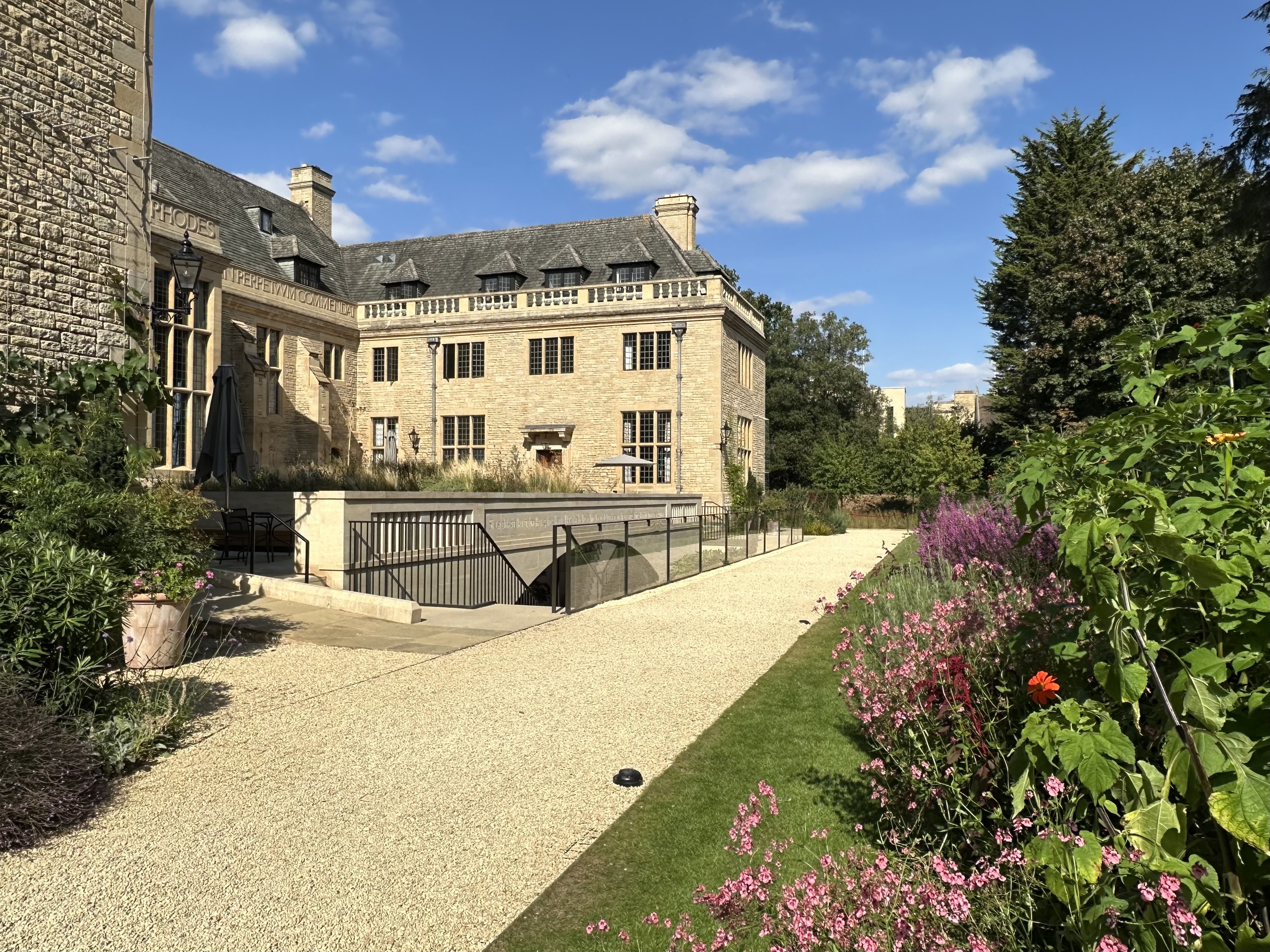 Back of Rhodes House with path and garden border full of flowers