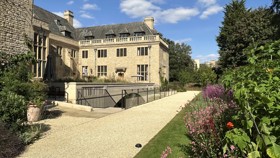 Back of Rhodes House with path and garden border full of flowers