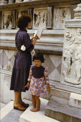 A picture showing Jaynie standing next to her little daughter, studying carved pillars and walls with a book in her hand