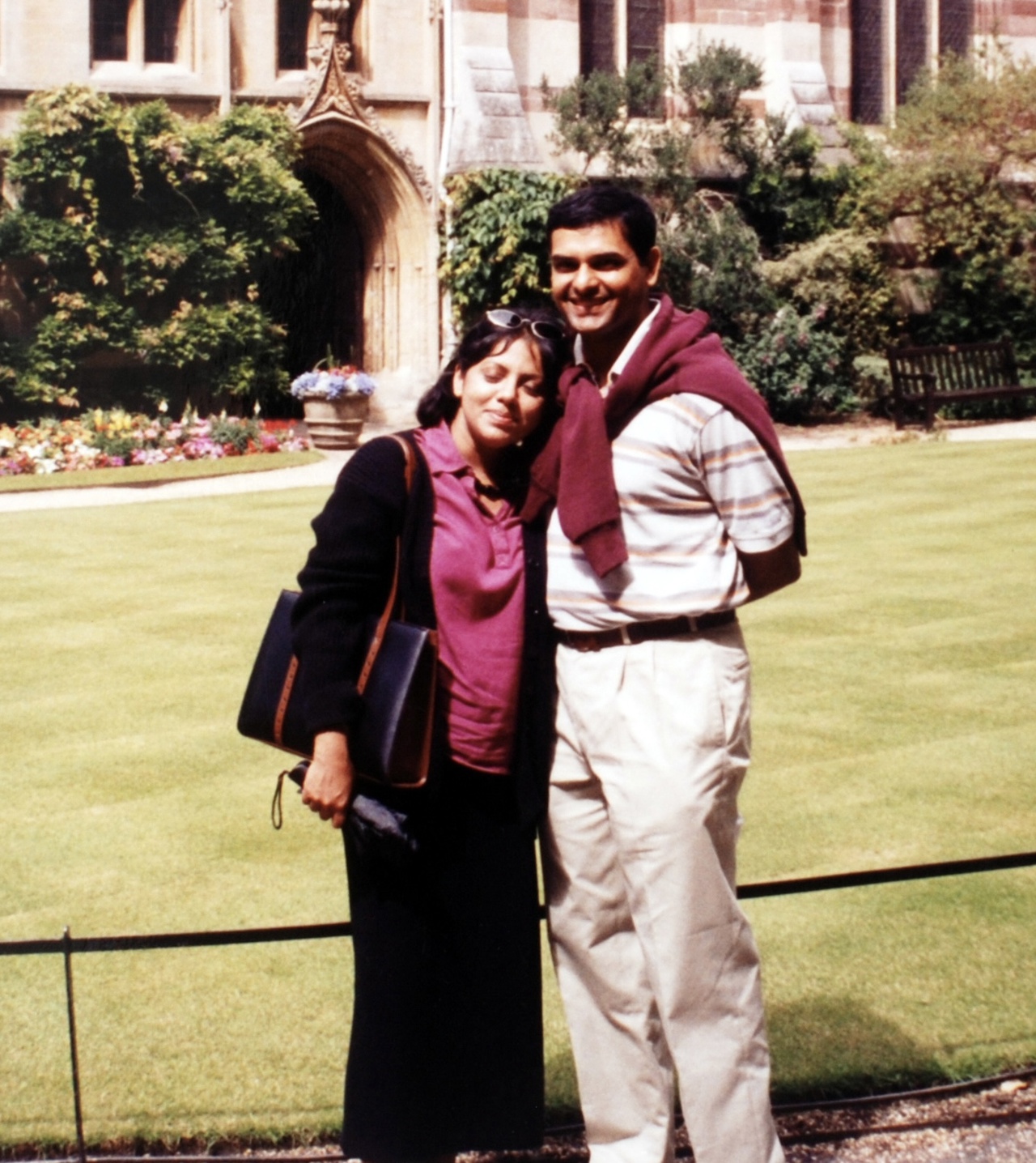 The picture shows Mukund with a red jumper tied around his shoulders. Saumya is leaning against him, with her head on his chest.