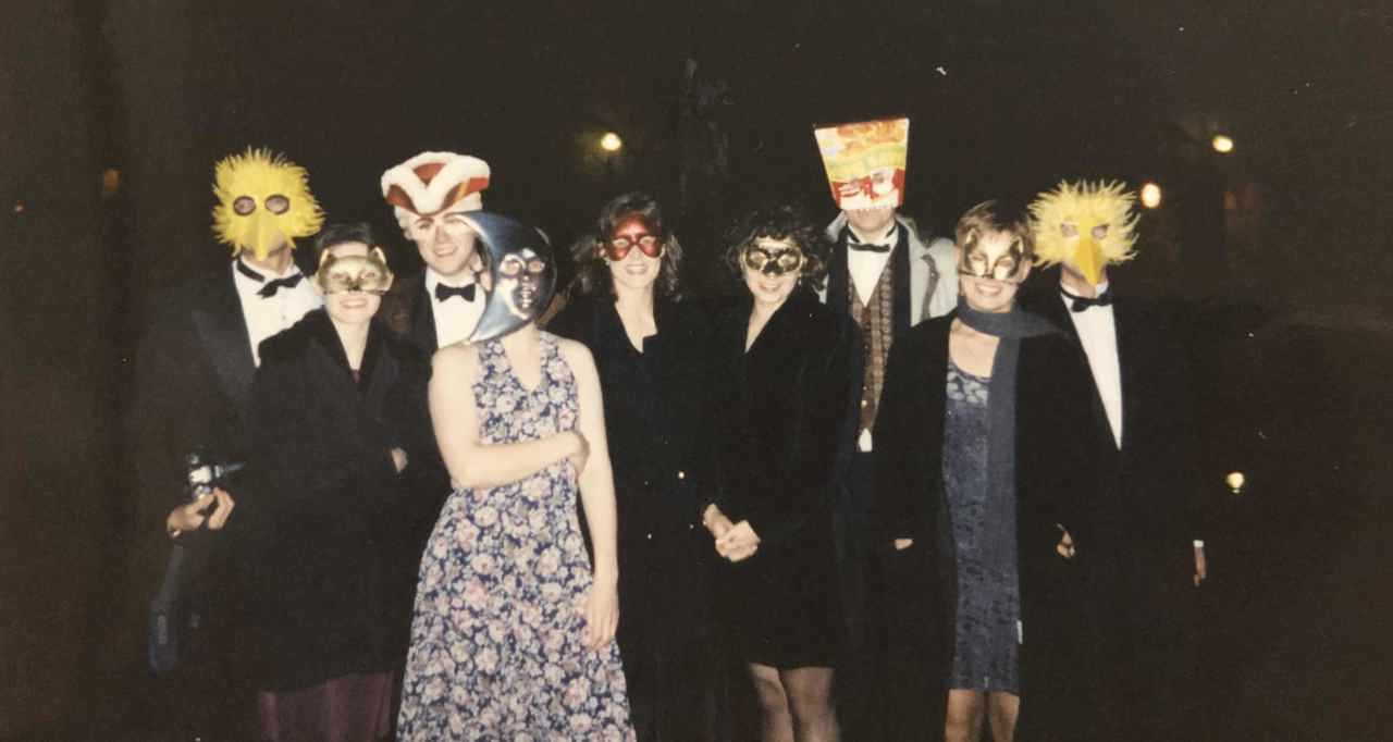 A picture showing young students in dresses and suits, with masks on their faces. Elle has a cat mask on.