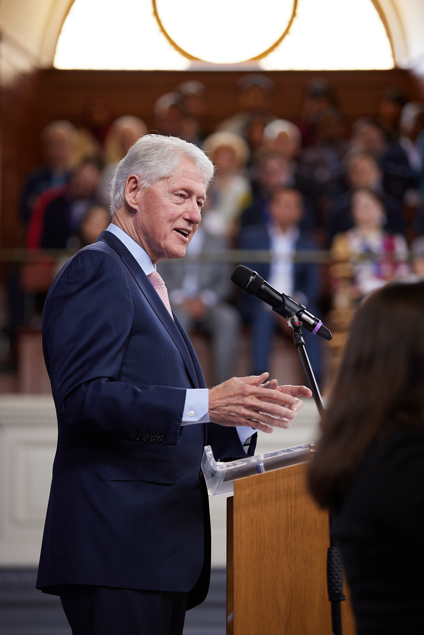 An image of American president Bill Clinton standing at a podium speaking to a conference room