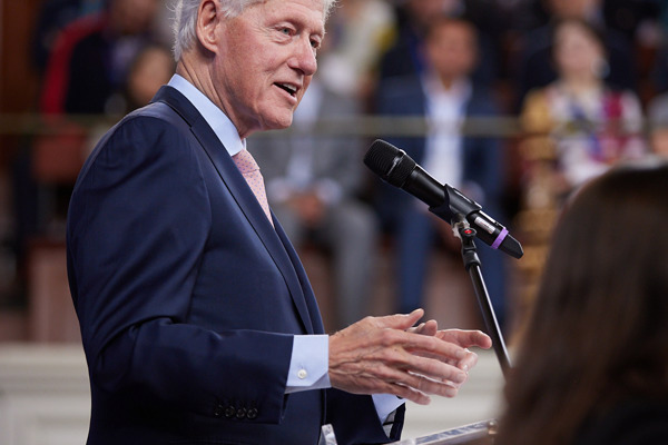An image of American president Bill Clinton standing at a podium speaking to a conference room