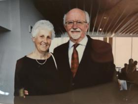 Andrew stood to the right in a black suit, with Christine to his left in a black dress. Both smiling.
