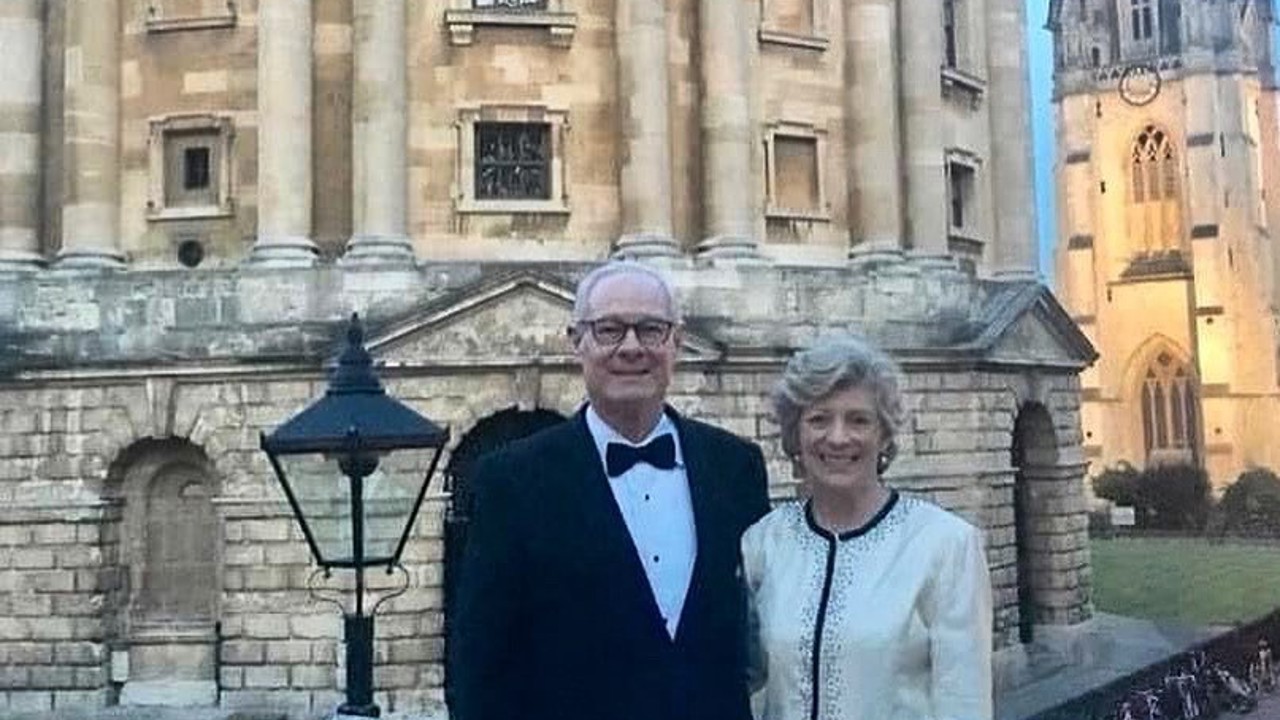 The picture shows Ralph in a black suit and Betsy in a white top and black pants, standing in front of the Radcliffe Camera. They are both smiling.