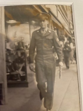 Black and white photo of a man in uniform walking down the street.
