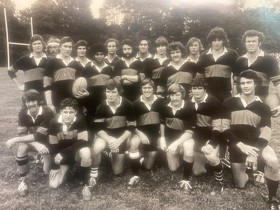 Black and white photo of university rugby team posing in their sports kit.