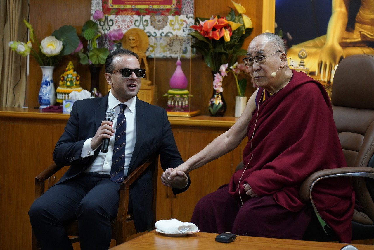 Cyrus Habib in conversation with the 14th Dalai Lama, holding his hand