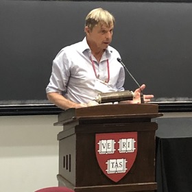 Geza stood at a podium giving a talk at Harvard.