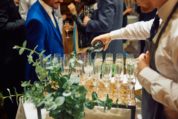 Sparkling wine being poured into glasses set up on a service table.