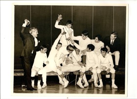 Black and white photo of group of young men fencing, wearing white.