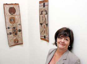 The picture shows Jaynie standing next to two specimens of indigenous art