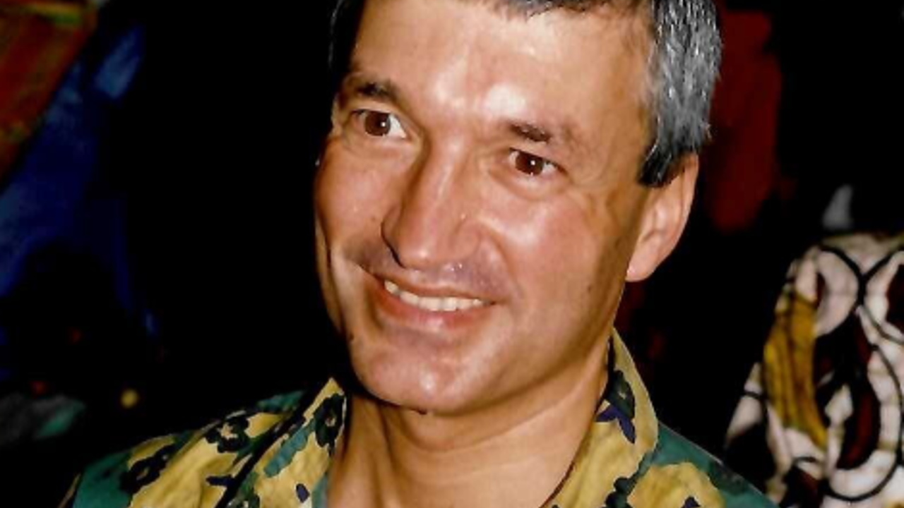 The picture shows Richard in a colorful green-and-yellow shirt with dark patterns. He is smiling at the camera.