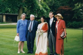The picture shows Mark in a suit with Shazia in a white gown and red top. She's holding flowers in her hands. Sir Kenny, his wife and Sally are standing around the couple, in formal wear.