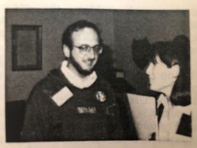 A black-and-white picture of Laurance in a jumper, talking to a woman