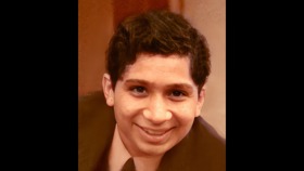 A sepia-toned picture of a young close-up shot of young Deepak's face, smiling