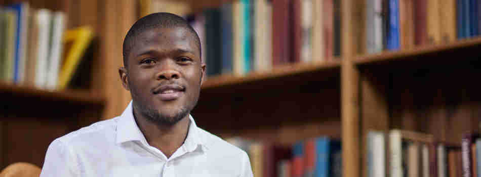 A man in a white shirt sitting in the Rhodes House library