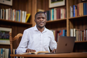 A Scholar in front of a laptop in the Rhodes House library