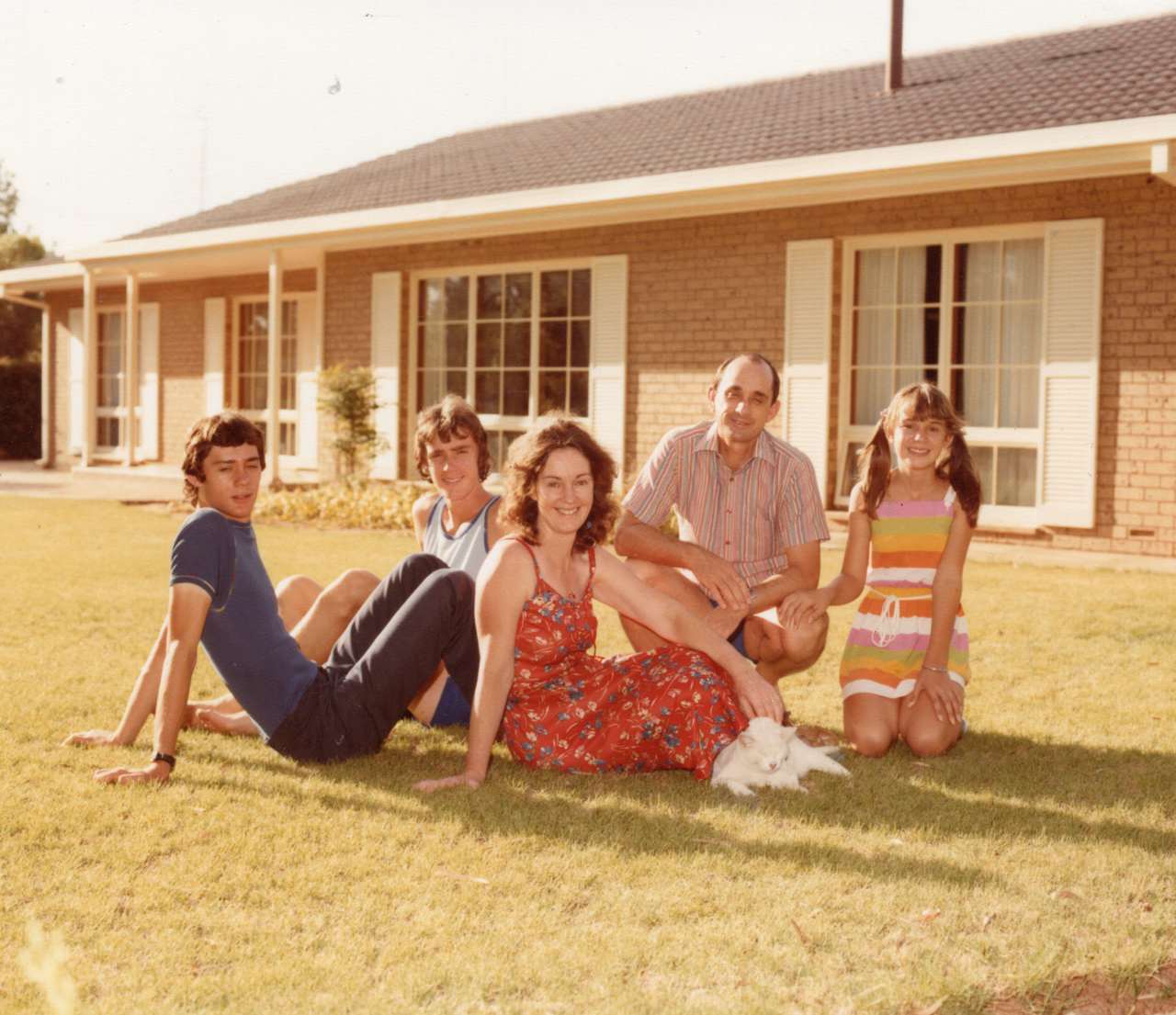 A picture showing a a man, a woman a little girl and two adolescent boys sitting on a lawn in front of a house in Port Pirie
