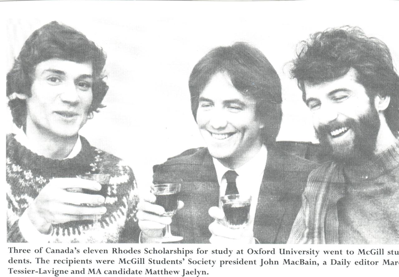 Black and white newspaper clipping. It pictures three young Scholars holding glasses of port, and John smiling in the middle. The text below reads: