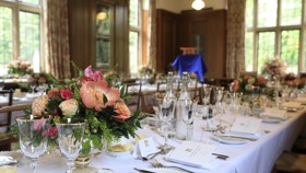 Beit Room dining tables with white cloths and pink flower arrangements.