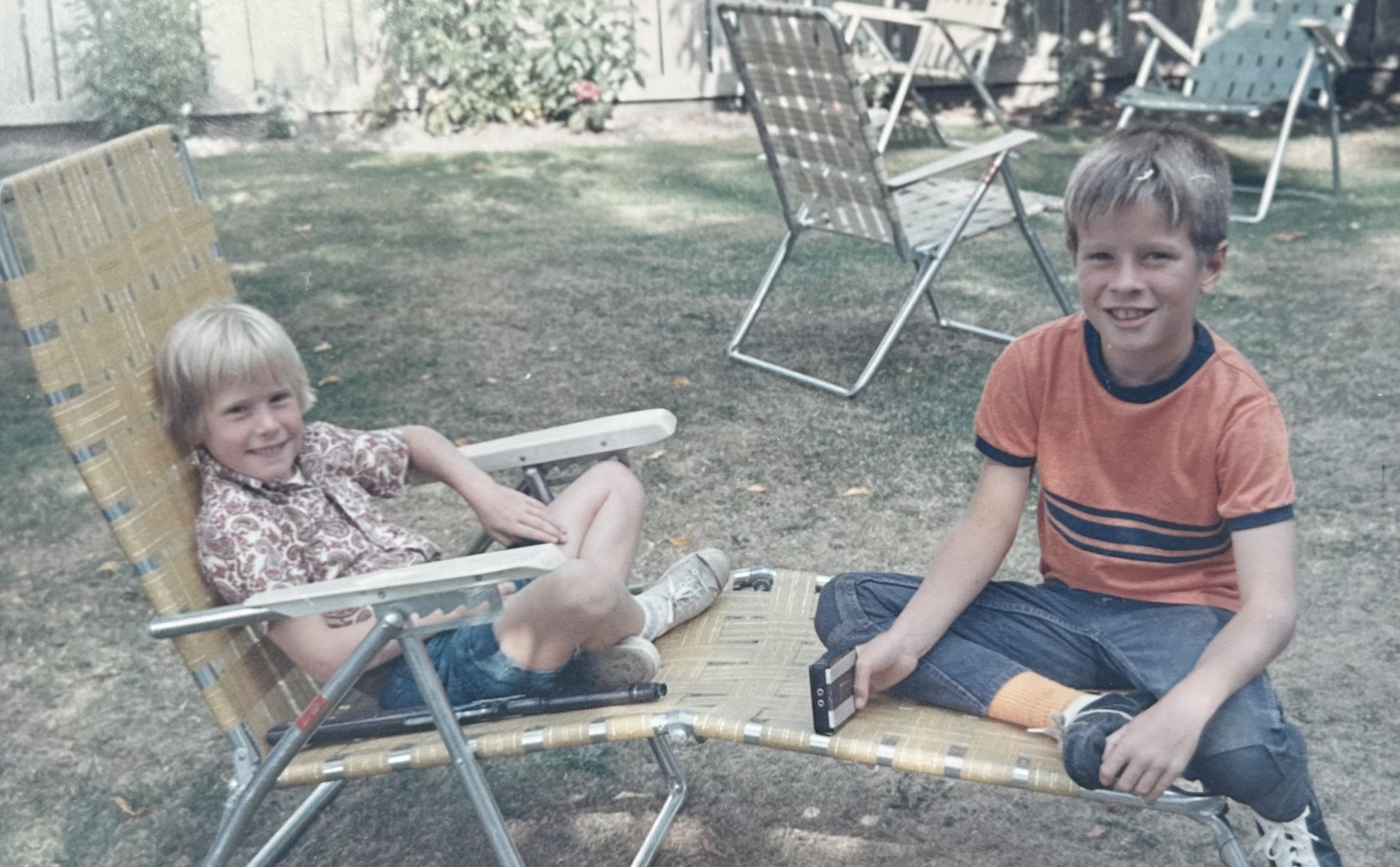 Meredith as a young girl sat to the left of her brother on a garden chair.
