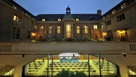 View of the Rhodes House courtyard and Conference Hall at night with windows lit, Hall set up for a conference.