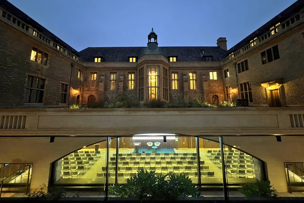 View of the Rhodes House courtyard and Conference Hall at night with windows lit, Hall set up for a conference.