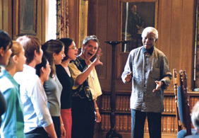 A smiling Nelson Mandela, greeting singing students at Rhodes House