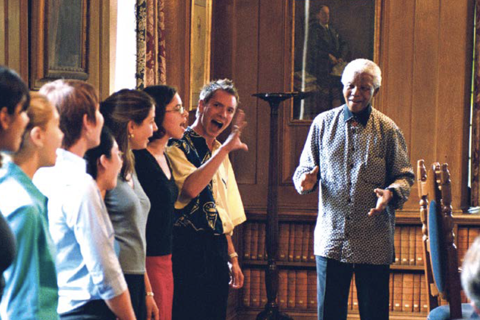 A smiling Nelson Mandela, greeting singing students at Rhodes House