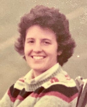 Grainy photo of Susan smiling wearing a stripy jumper