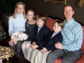 Bob seated with his wife, three children and dog on a sofa