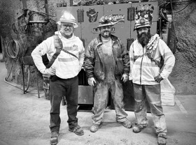 A black-and-white picture of Charles and two other men inside the Stillwater mine, with helmets and mining gear