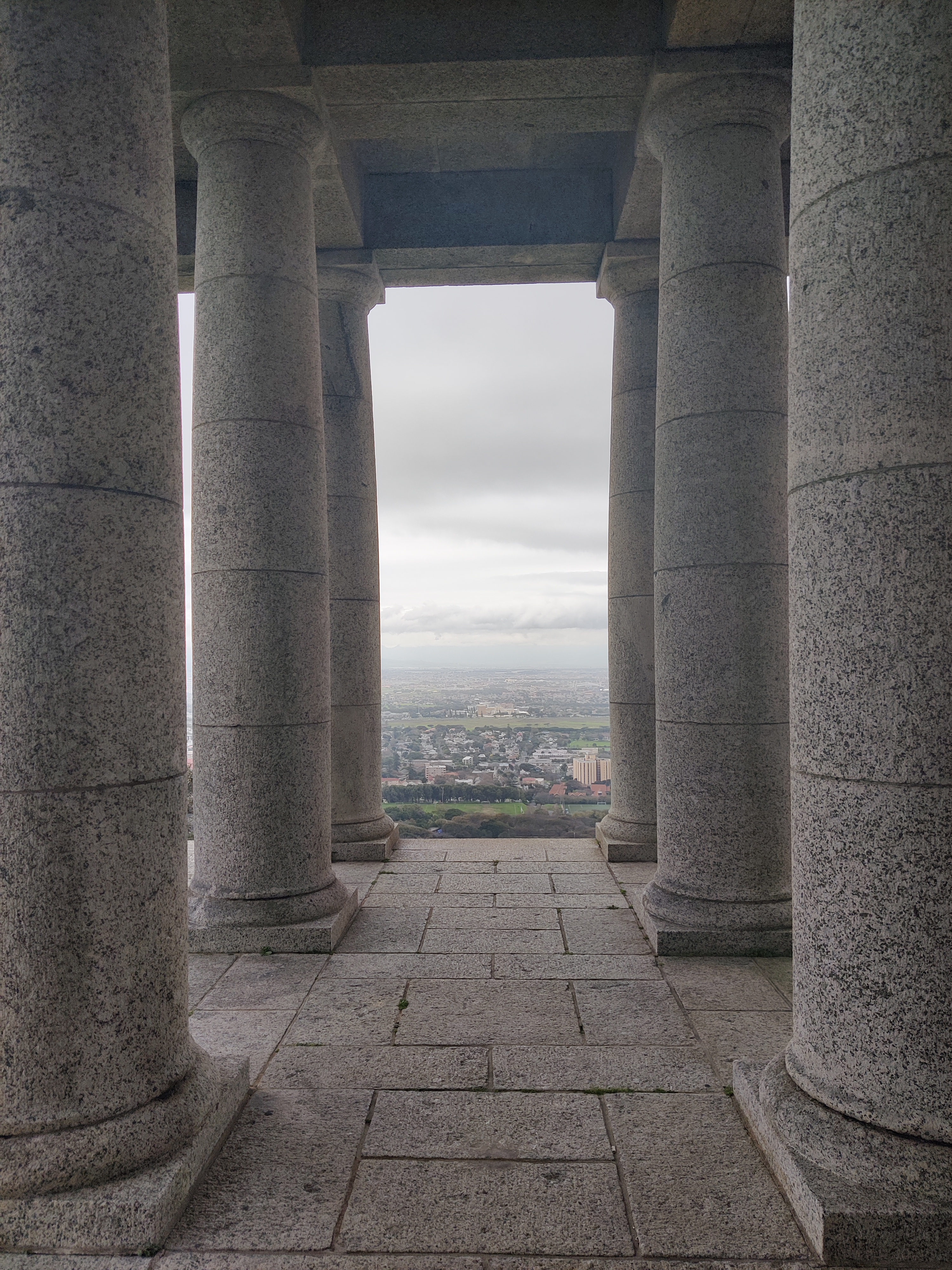 A view of Cape Town under overcast skies from between the large imposing pillars at The Rhodes Memorial.