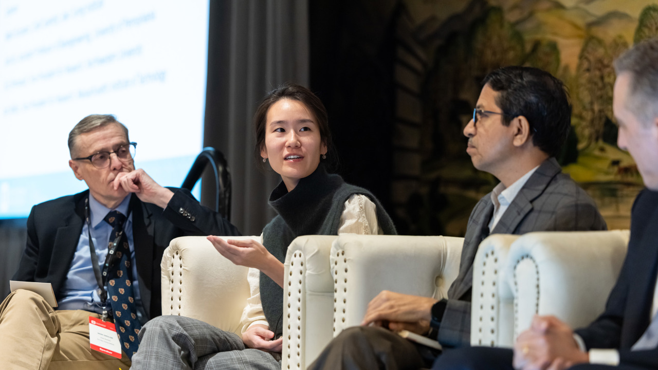 Three people in conversation, seated onstage for a panel discussion.