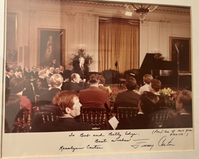 Bob sitting in a packed hall with Jimmy Carter delivering a speech